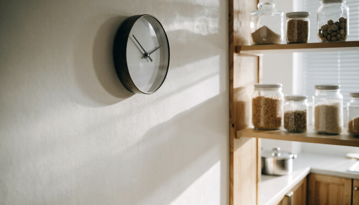 Horloge murale ronde dans une cuisine claire, au-dessus d'étagères ouvertes Image