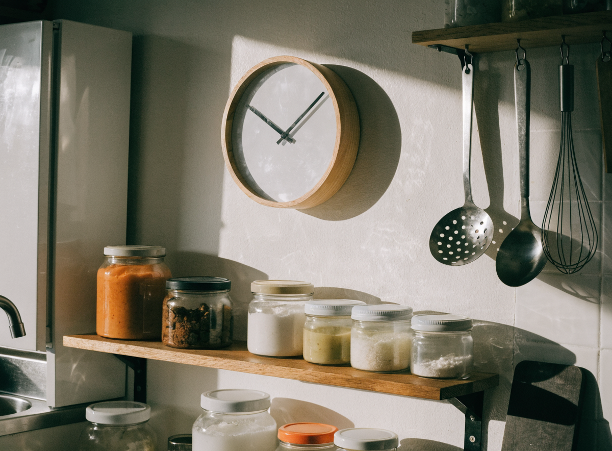 Horloge murale ronde dans une cuisine, au-dessus d étagères ouvertes Image